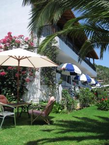 a patio with a table and chairs and an umbrella at Skiathos Studios Panorama in Skiathos