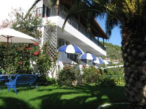 a building with umbrellas and a bench in the grass at Skiathos Studios Panorama in Skiathos +14 photos