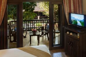 a room with a bed and a television and a balcony at Lanna Dusita Riverside Boutique Resort in Chiang Mai