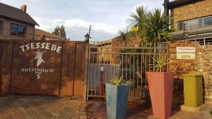 een houten poort met planten voor een gebouw bij Tsessebe Guesthouse in Bloemfontein