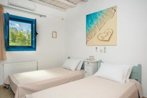 two beds in a room with a window at Paradis beach home in Molos Parou
