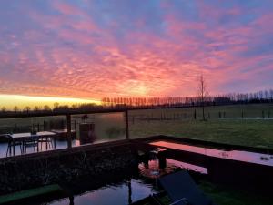 un coucher de soleil sur un étang avec une table et une table dans l'établissement B&B Finis terrae, à Lokeren