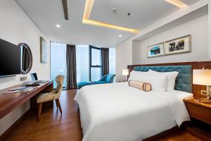 a hotel room with a large bed and a desk at Paris Deli Danang Beach Hotel in Danang