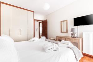 a white bedroom with two beds and a flat screen tv at DN Sea Apartments in Kalamata