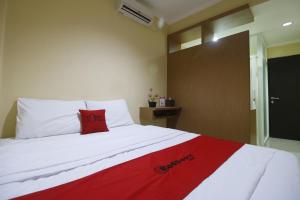 Una cama con una almohada roja encima. en RedDoorz near ITC Cempaka Mas, en Yakarta