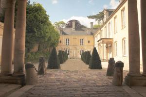 a courtyard of a castle with trees and a building at Le Tardif, Noble Guesthouse in Bayeux