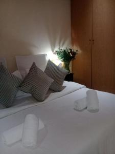 a white bed with two pillows and a vase with flowers at Shalamanzi Lodge in Hartbeespoort