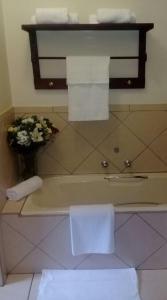 a bathroom with a tub with towels and a vase of flowers at Shalamanzi Lodge in Hartbeespoort