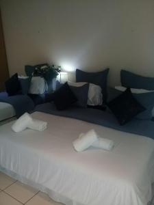 a large white bed with pillows and a blue couch at Shalamanzi Lodge in Hartbeespoort