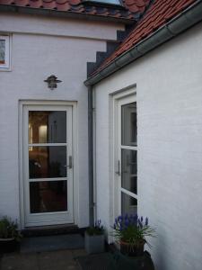 uma casa branca com uma porta e algumas flores em Natursti Silkeborg Bed & Breakfast em Them