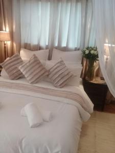 a white bed with four pillows on it at Shalamanzi Lodge in Hartbeespoort