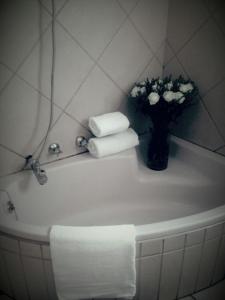 a bathroom sink with a vase of flowers and towels at Shalamanzi Lodge in Hartbeespoort