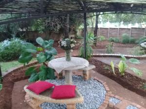 a table with a vase of flowers in a garden at Shalamanzi Lodge in Hartbeespoort