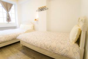 a bed room with a white bedspread and pillows at Hualien Bird's House Hostel in Hualien City