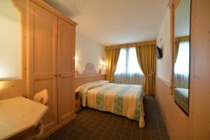 pokój hotelowy z łóżkiem i komodą w obiekcie Hotel Dalla Serra w mieście Mezzana