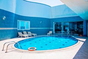 a large swimming pool in a room with chairs at Platinum Hotel Apartments in Abu Dhabi