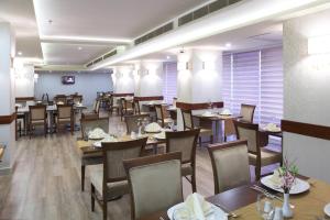 a dining room with tables and chairs in a restaurant at Hotel Senbayrak City in Adana
