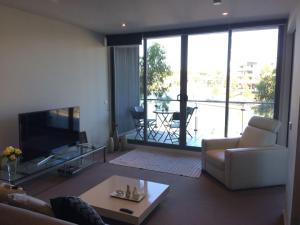 a living room with a couch and a tv at Marina View Apartment on the Maribyrnong River, Melbourne in Maribyrnong