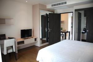 um quarto com uma cama, uma secretária e uma televisão em Park Village Rama II em Bangkok