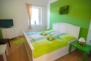 1 dormitorio con 1 cama con pared verde en Fontana Pizzeria - Pension, en České Budějovice