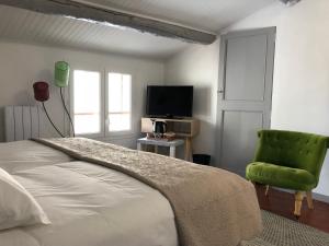 a bedroom with a bed and a green chair at La maison de jules in Moustiers-Sainte-Marie