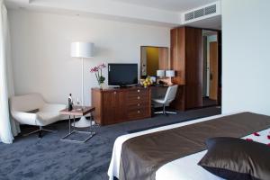 a hotel room with a bed and a desk and a tv at Lighthouse Golf & Spa Hotel in Balchik
