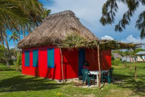Yasawa Homestays في Nacula Island: كوخ صغير مع امرأة تجلس على طاولة