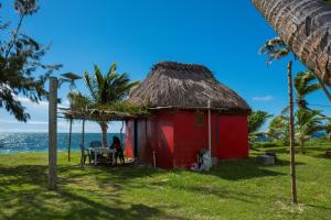 una capanna rossa sulla spiaggia con l'oceano di Yasawa Homestays a Nacula Island