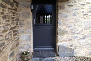 a black door in a stone building with a stone wall at The Buttery at Trussel Barn in Liskeard