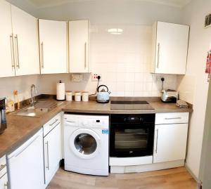 a kitchen with white cabinets and a dishwasher at The Wee Highland Coo in Edinburgh