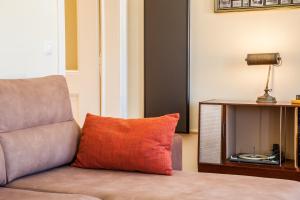 a couch with a orange pillow sitting next to a table at ALTIDO Fernando Pessoa Apartments in Lisbon