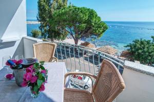 a table with flowers on a balcony with the ocean at Hotel Ristorante La Conchiglia in Cala Gonone
