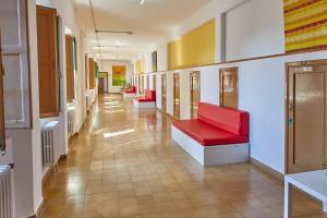 un couloir d'un hôpital avec des chaises rouges dans un couloir dans l'établissement Albergue Seminario Menor, à Saint-Jacques-de-Compostelle