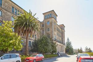 un gran edificio de ladrillo con coches estacionados frente a él en Albergue Seminario Menor, en Santiago de Compostela