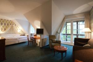 a hotel room with a bed and a desk and chairs at Romantik Hotel Hof zur Linde in Münster +117 photos