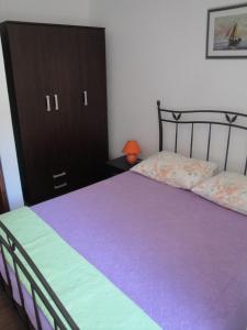 a bedroom with a purple bed and a black cabinet at Apartments Niki - 5m from the sea in Drvenik Veli