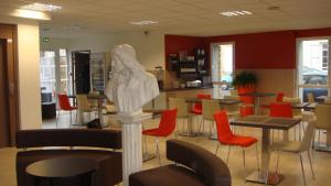 a restaurant with tables and chairs and a statue in the middle at The Originals Access, H&ocirc;tel Cholet Gare in Cholet