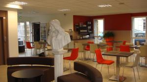 a restaurant with tables and chairs and a statue in the middle at The Originals Access, Hôtel Cholet Gare in Cholet