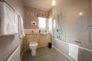 a bathroom with a toilet and a shower and a sink at Taigh Mhuirne in Portree +10 photos
