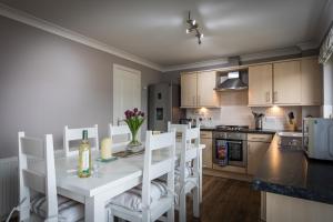 a kitchen with a white dining room table and chairs at Taigh Mhuirne in Portree