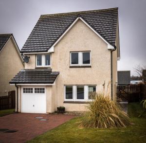 a brick house with a white garage at Taigh Mhuirne in Portree