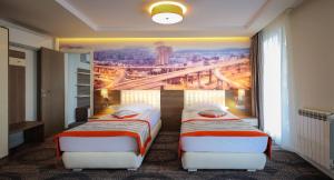 two beds in a hotel room with a painting on the wall at Plaza35 in Sibiu