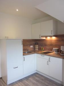 a kitchen with white cabinets and a wooden wall at Hotel Wolfsschlucht in Baden-Baden