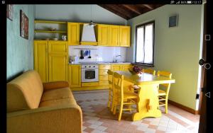 a kitchen with yellow cabinets and a table and chairs at Agricola Lanciani in Montefiore dellʼAso
