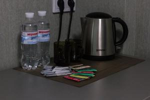ein Regal mit einer Kaffeekanne und Wasserflaschen darauf in der Unterkunft Solo Apartment Ahmatovoy in Kiew