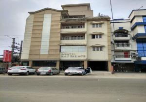 迪布鲁加尔Hotel Raj Palace的一座大楼，前面停满了汽车