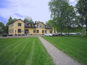 una gran casa amarilla con un césped verde delante de ella en Karlsborgs vandrarhem och B&B, en Karlsborg