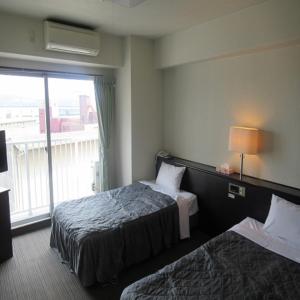 大分市にある鶴崎ホテルのベッド2台と窓が備わるホテルルームです。