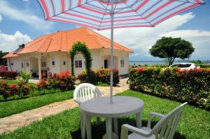 a table with an umbrella in front of a house at Victoria Lake View Guesthouse & Safaris in Entebbe
