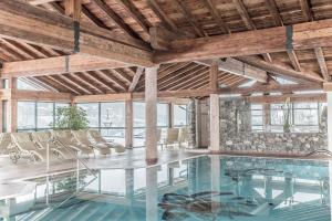 een binnenzwembad met stoelen in een gebouw met houten plafonds bij Hotel Elisabeth, 4 Sterne Superior in Kirchberg in Tirol